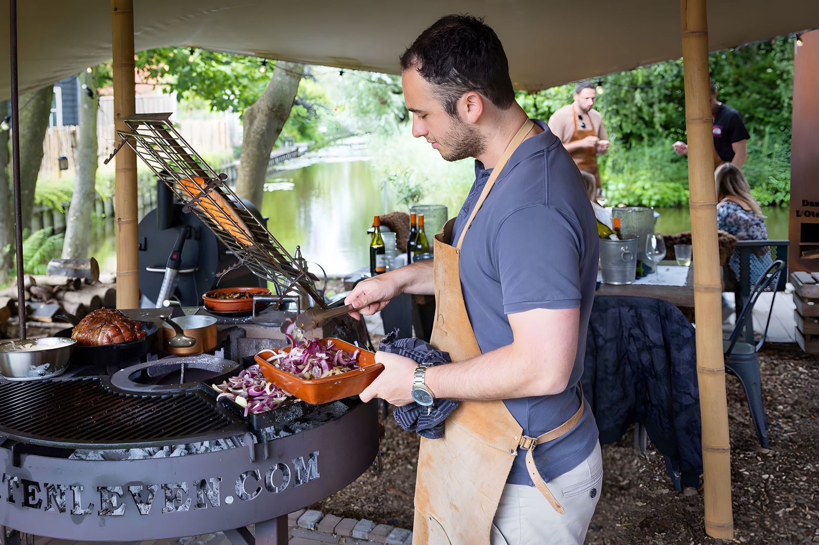 Aan de grill in de buitenkeuken onder de stretchtent, met leren schort