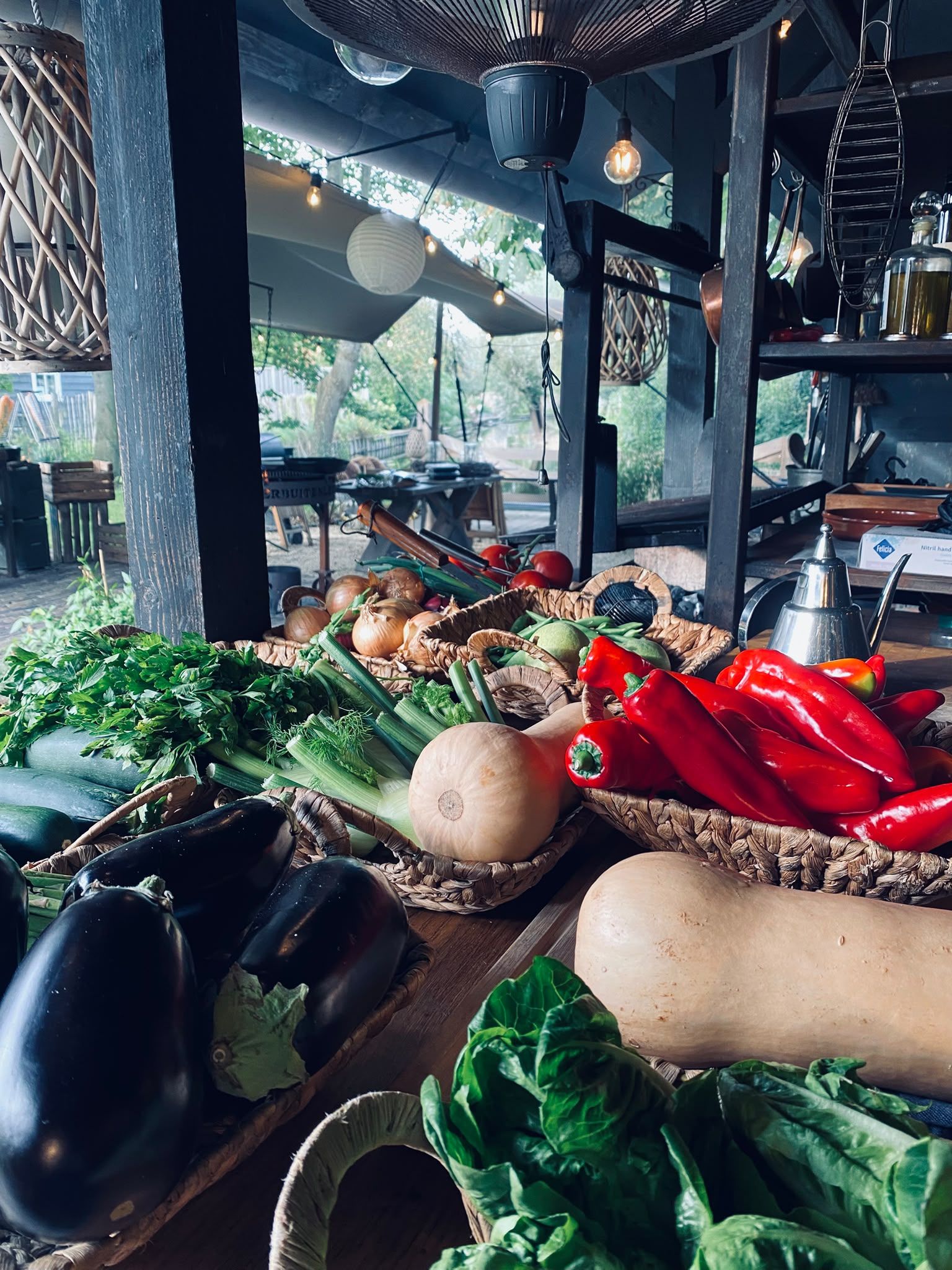Verse groenten op tafel in de buitenkeuken: paprika, aubergine, pompoen en snijbiet